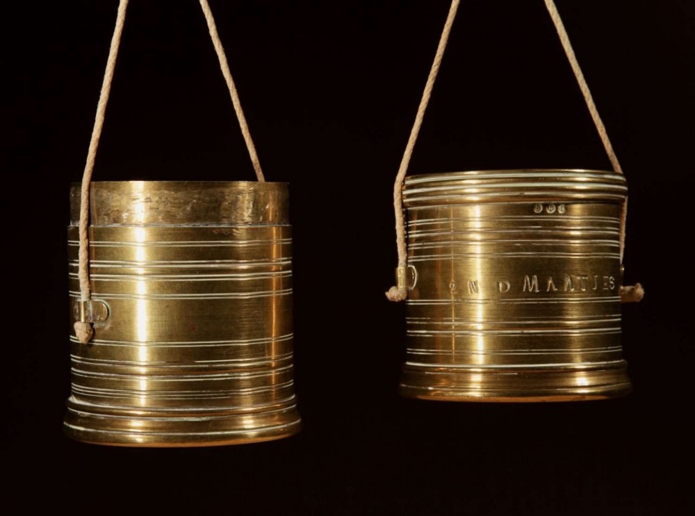 An 1846 Dutch brass bushel balance set featuring a balance beam, two cylindrical brass measuring buckets, calibrated brass weights, a wooden striker, and a striped fabric pouch. View VI