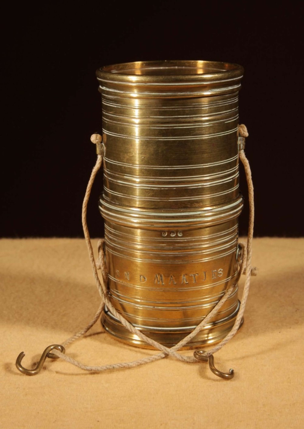 An 1846 Dutch brass bushel balance set featuring a balance beam, two cylindrical brass measuring buckets, calibrated brass weights, a wooden striker, and a striped fabric pouch. View IX