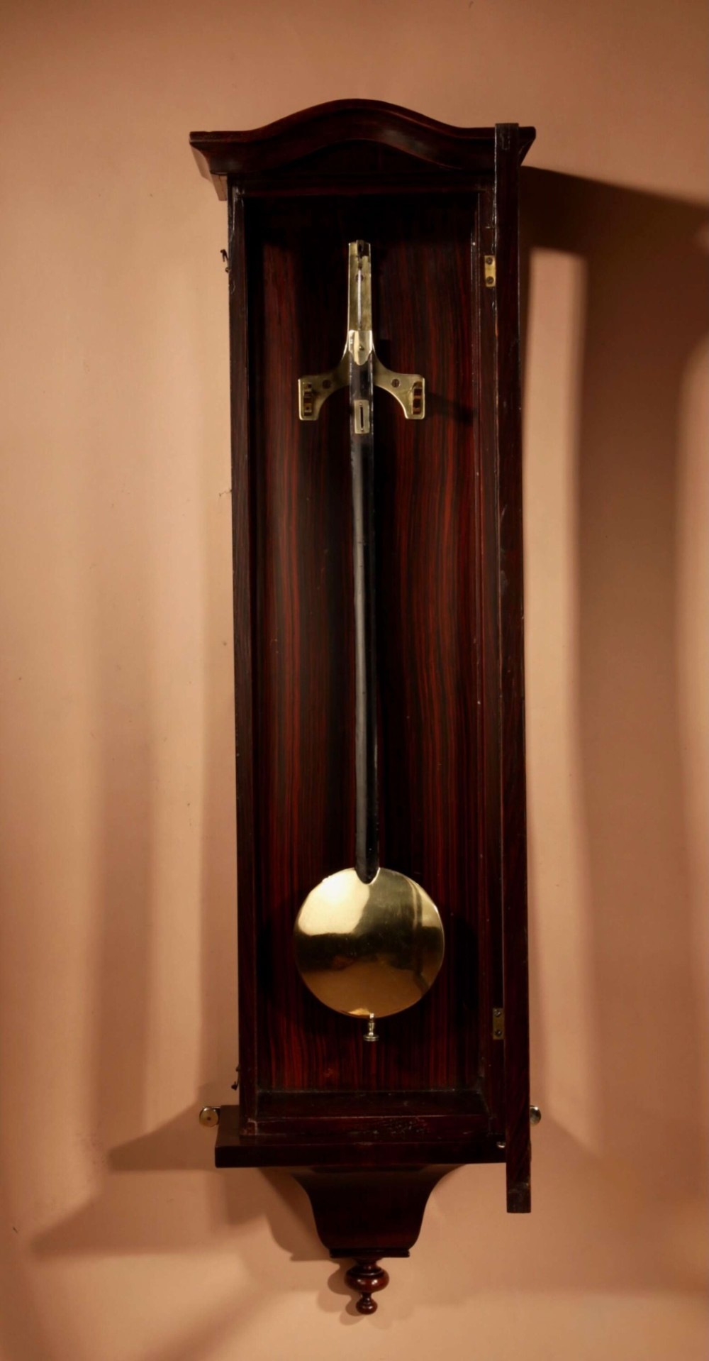 An antique dark wood Vienna regulator wall clock featuring a glazed case, white enamel dial with Roman numerals, and a polished brass pendulum. View II