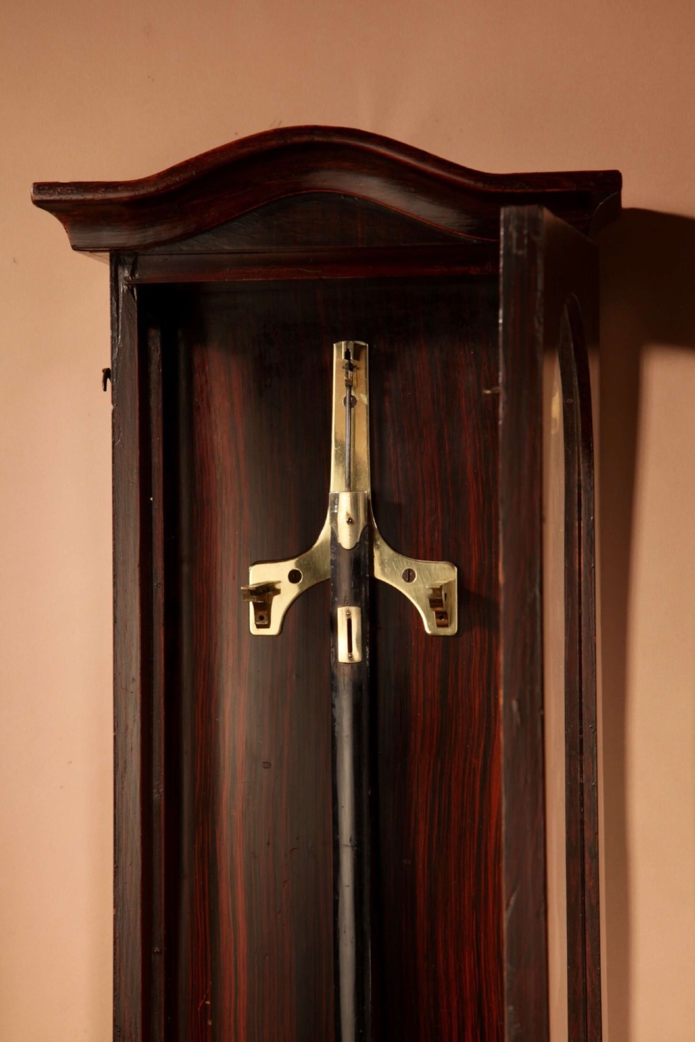 An antique dark wood Vienna regulator wall clock featuring a glazed case, white enamel dial with Roman numerals, and a polished brass pendulum. View III