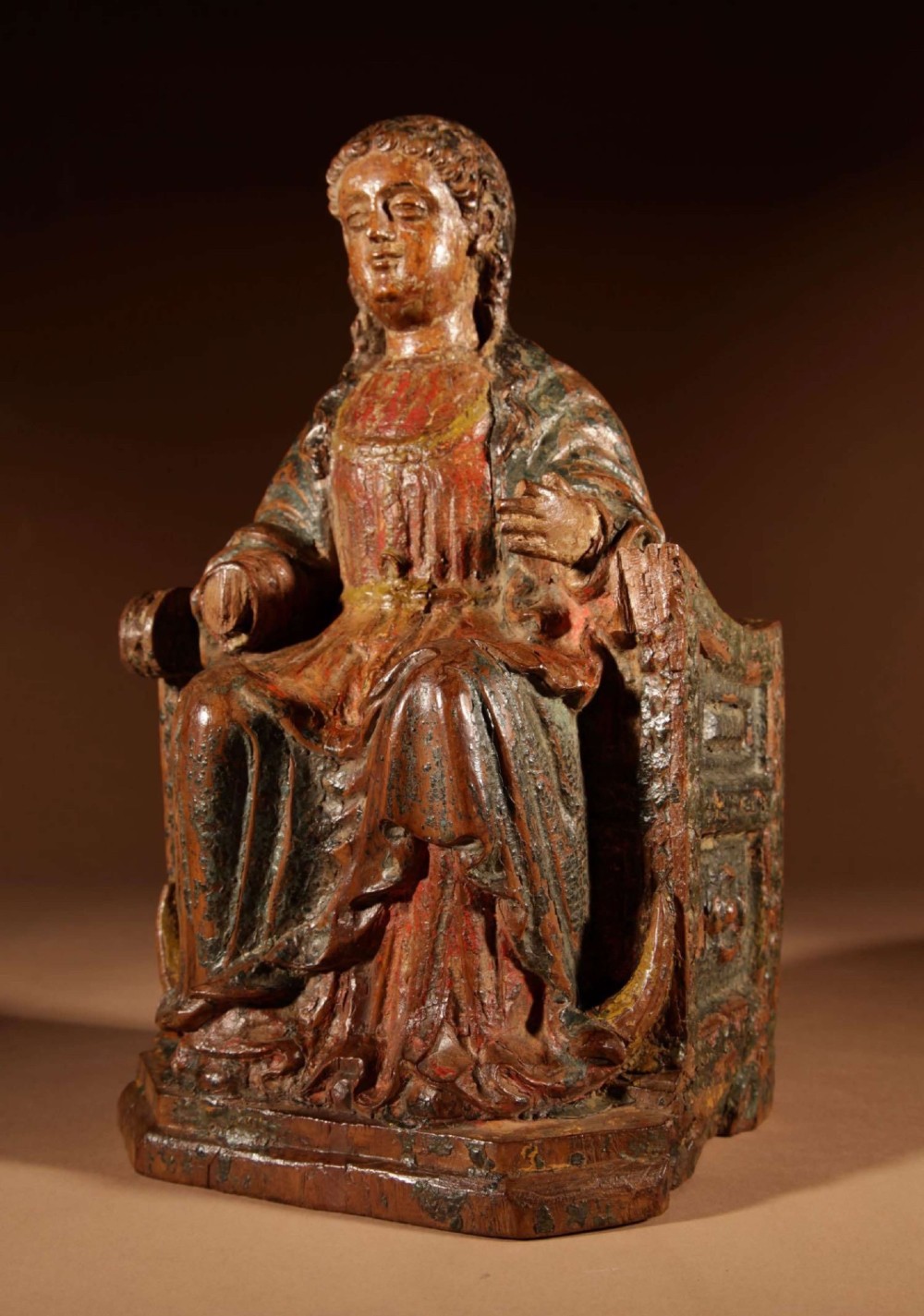 A 16th-century carved walnut statue depicting the Madonna seated on a throne with visible remnants of red and green polychrome paint. View X