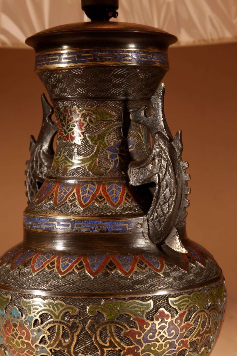 An antique Japanese bronze urn converted into a table lamp, featuring colourful Champleve enamel motifs, twin handles, and a cream pleated shade. View V