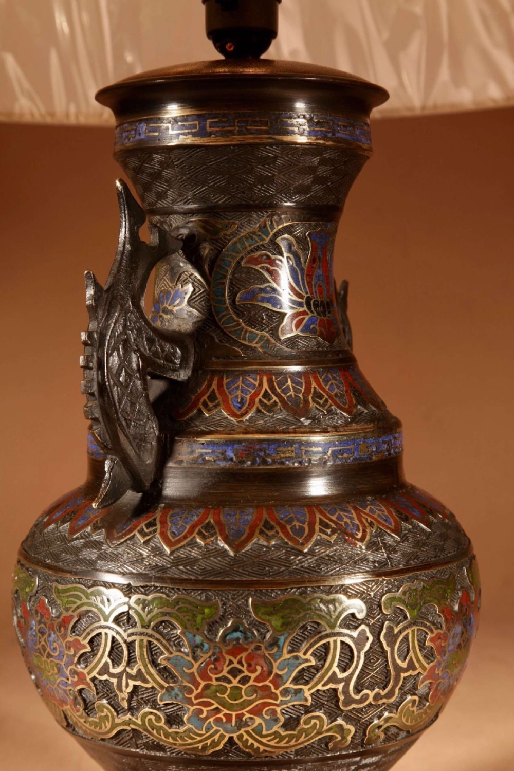An antique Japanese bronze urn converted into a table lamp, featuring colourful Champleve enamel motifs, twin handles, and a cream pleated shade. View VI