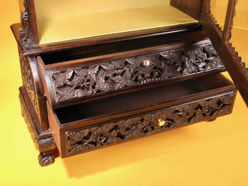 A 19th-century Anglo-Indian dark hardwood small display cabinet featuring intricate pierced foliate carvings, an arched pediment, a glazed four-pane door with scalloped moulding, and two carved drawers at the base. View IV