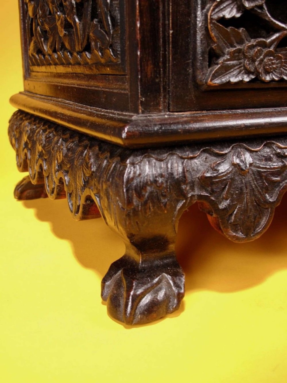 A 19th-century Anglo-Indian dark hardwood small display cabinet featuring intricate pierced foliate carvings, an arched pediment, a glazed four-pane door with scalloped moulding, and two carved drawers at the base. View VI
