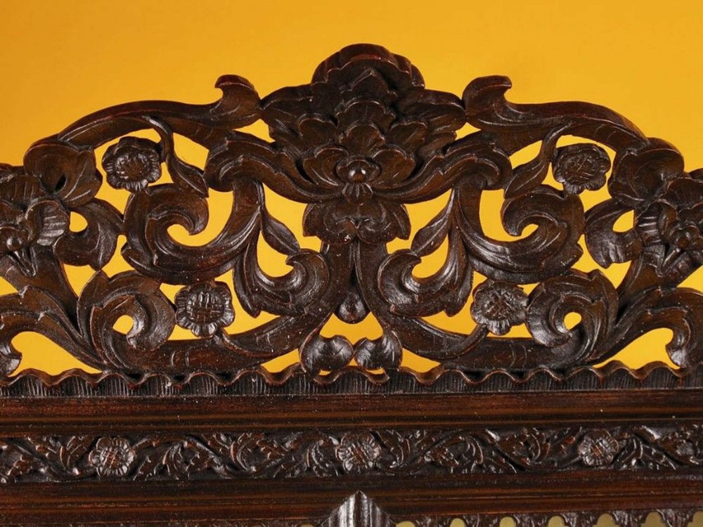 A 19th-century Anglo-Indian dark hardwood small display cabinet featuring intricate pierced foliate carvings, an arched pediment, a glazed four-pane door with scalloped moulding, and two carved drawers at the base. View VII