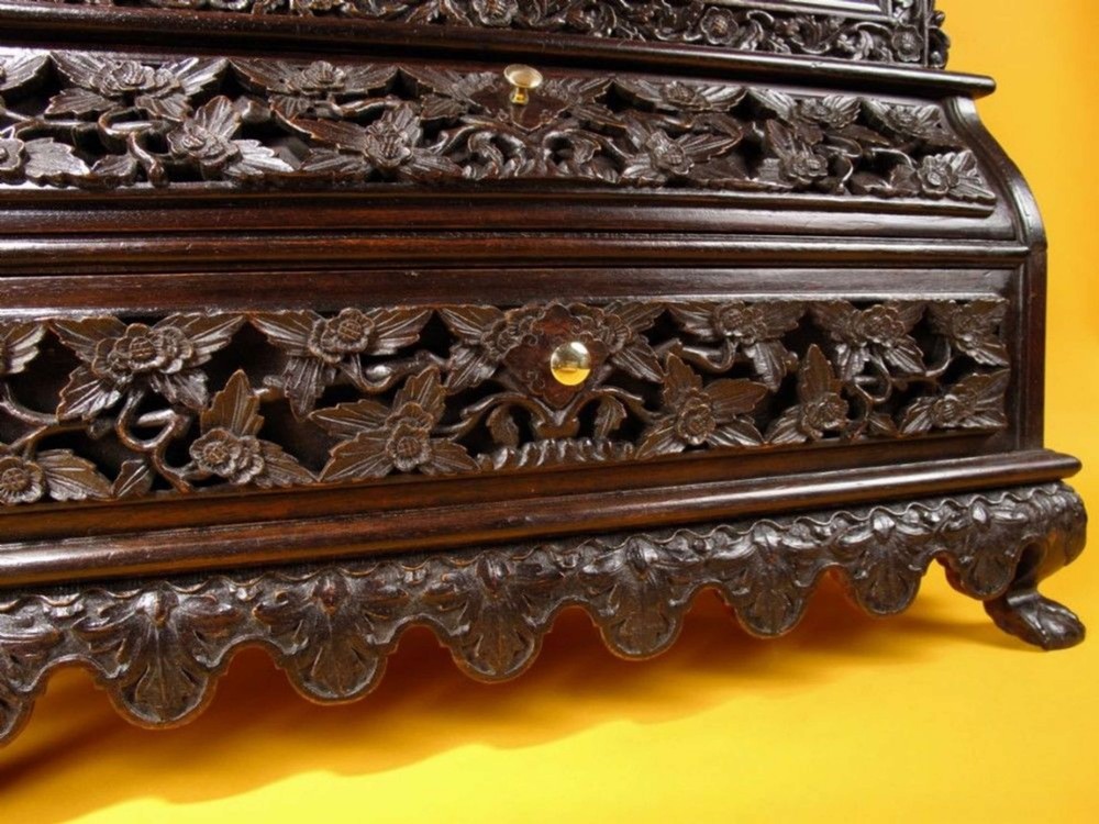 A 19th-century Anglo-Indian dark hardwood small display cabinet featuring intricate pierced foliate carvings, an arched pediment, a glazed four-pane door with scalloped moulding, and two carved drawers at the base. View XII