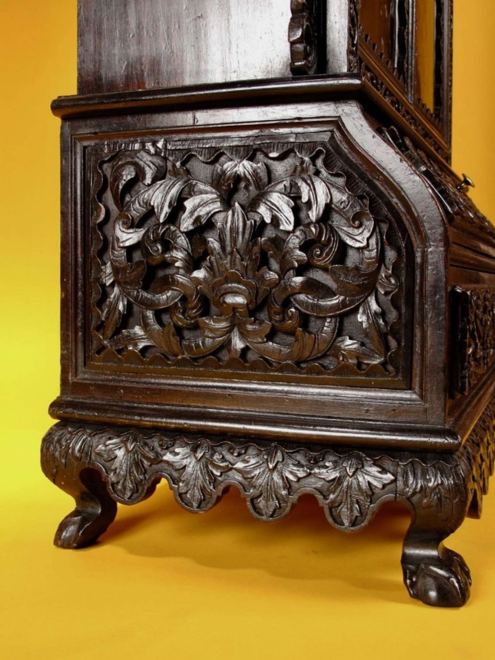 A 19th-century Anglo-Indian dark hardwood small display cabinet featuring intricate pierced foliate carvings, an arched pediment, a glazed four-pane door with scalloped moulding, and two carved drawers at the base. View XIII