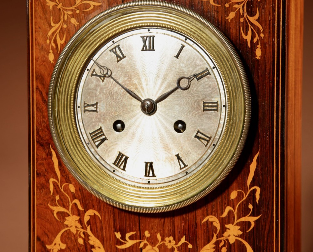 An antique Charles X rosewood mantel clock featuring intricate floral marquetry inlays, a silvered Roman numeral dial, and a decorative cast brass handle on top. View III