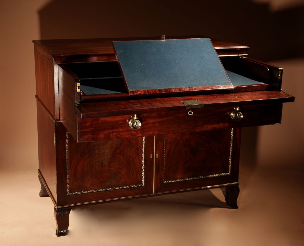A Regency mahogany library secretaire featuring a pull-out writing drawer with an adjustable slope, brass handles, and lower cabinet doors opening to reveal pull-out tray shelves. View IV
