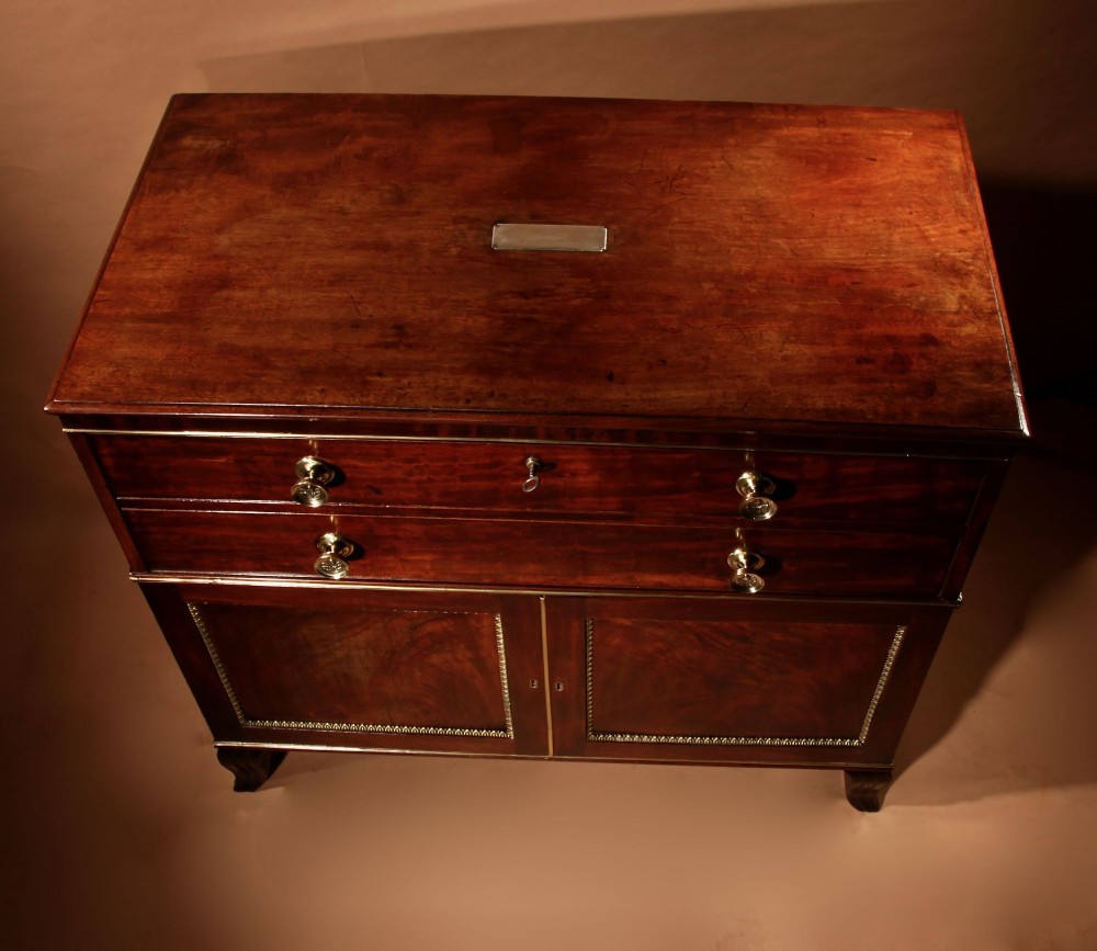 A Regency mahogany library secretaire featuring a pull-out writing drawer with an adjustable slope, brass handles, and lower cabinet doors opening to reveal pull-out tray shelves. View VII
