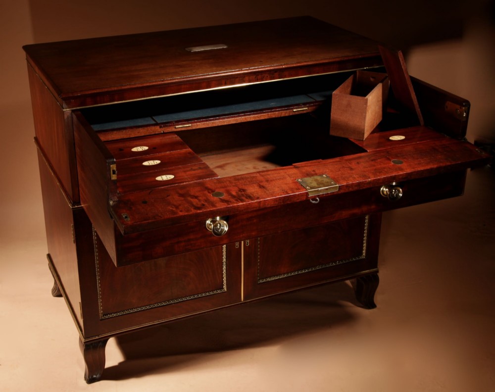 A Regency mahogany library secretaire featuring a pull-out writing drawer with an adjustable slope, brass handles, and lower cabinet doors opening to reveal pull-out tray shelves. View X