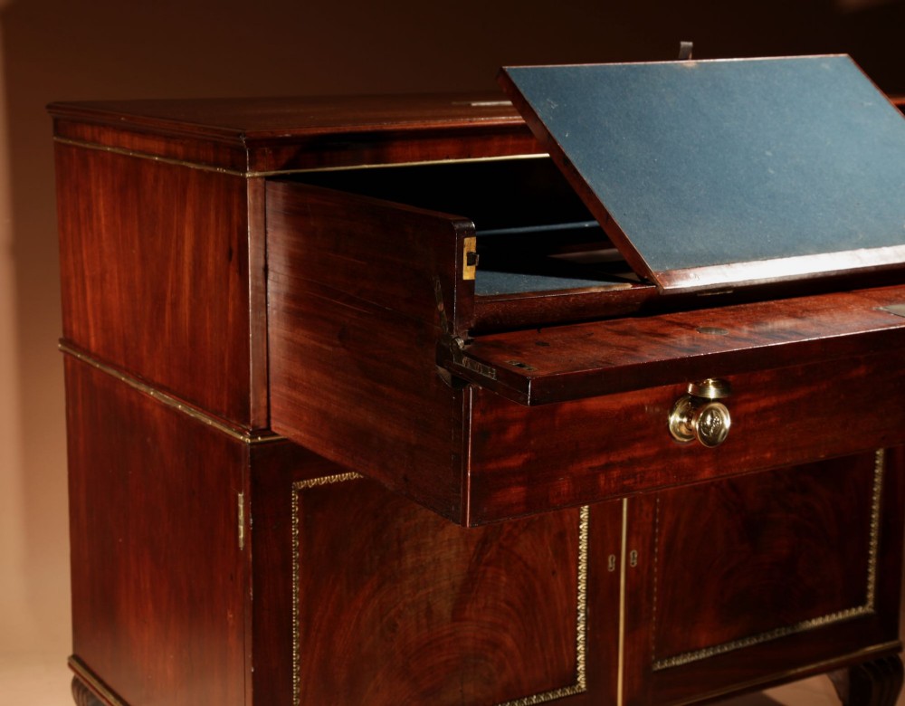 A Regency mahogany library secretaire featuring a pull-out writing drawer with an adjustable slope, brass handles, and lower cabinet doors opening to reveal pull-out tray shelves. View XV
