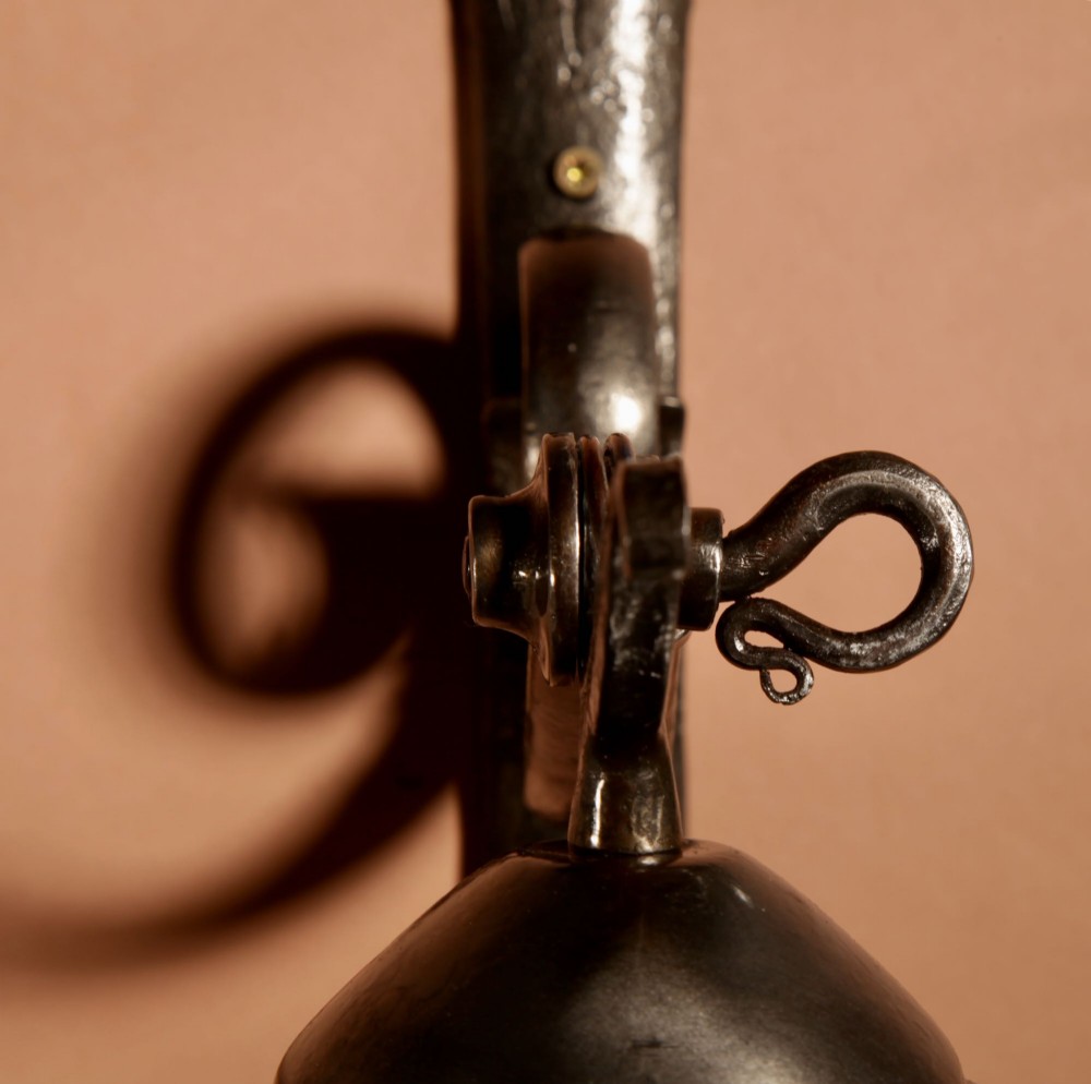 A pair of Art Deco wrought iron wall sconces featuring curved scroll arms and conical pleated cream fabric shades mounted on wall brackets. View IV