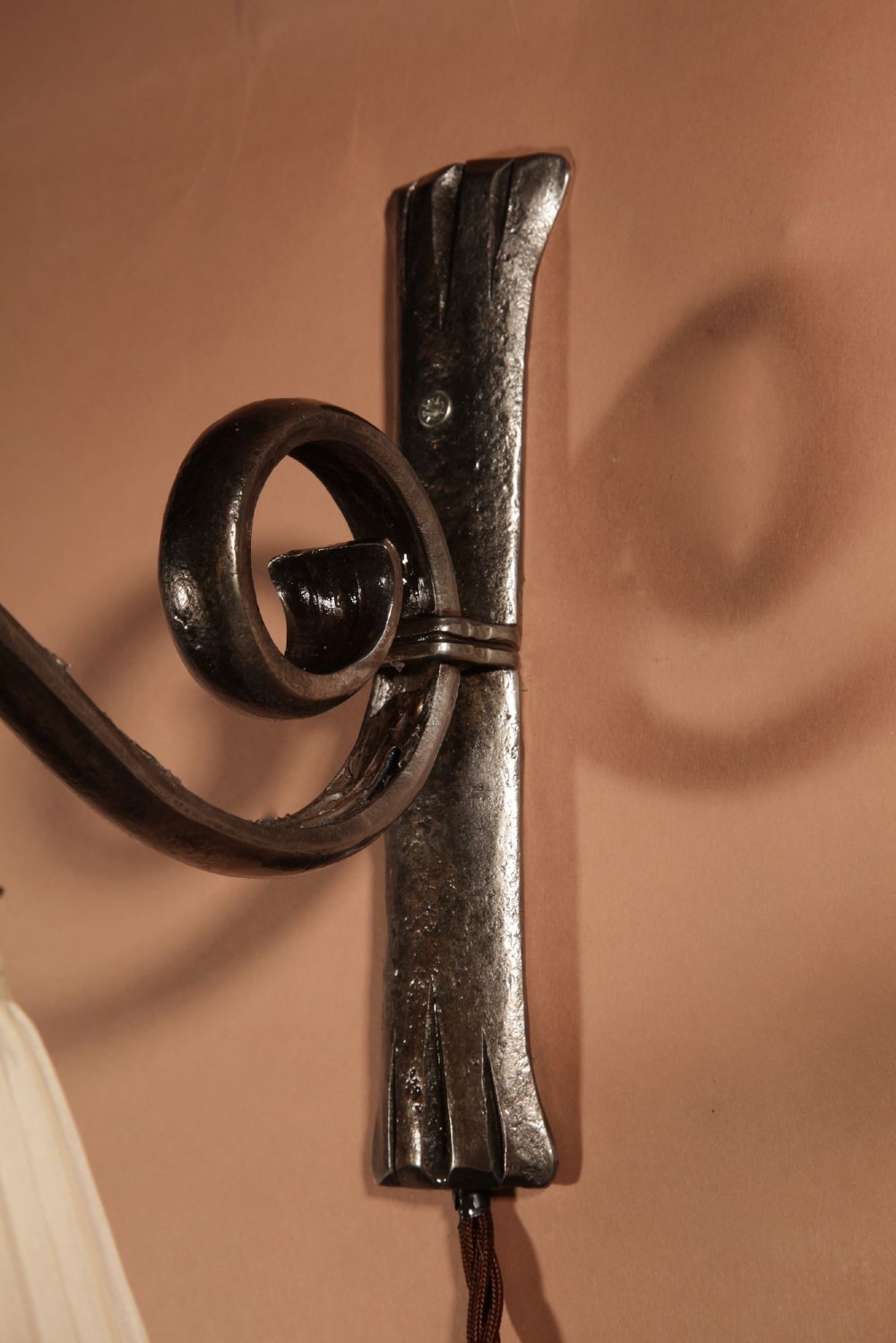 A pair of Art Deco wrought iron wall sconces featuring curved scroll arms and conical pleated cream fabric shades mounted on wall brackets. View VII