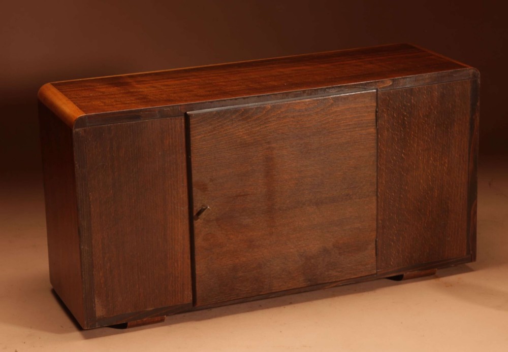 A horizontal rectangular Art Deco walnut mantel clock with applied chrome Arabic numerals, chrome hands, and polished metal bracket feet. View IV