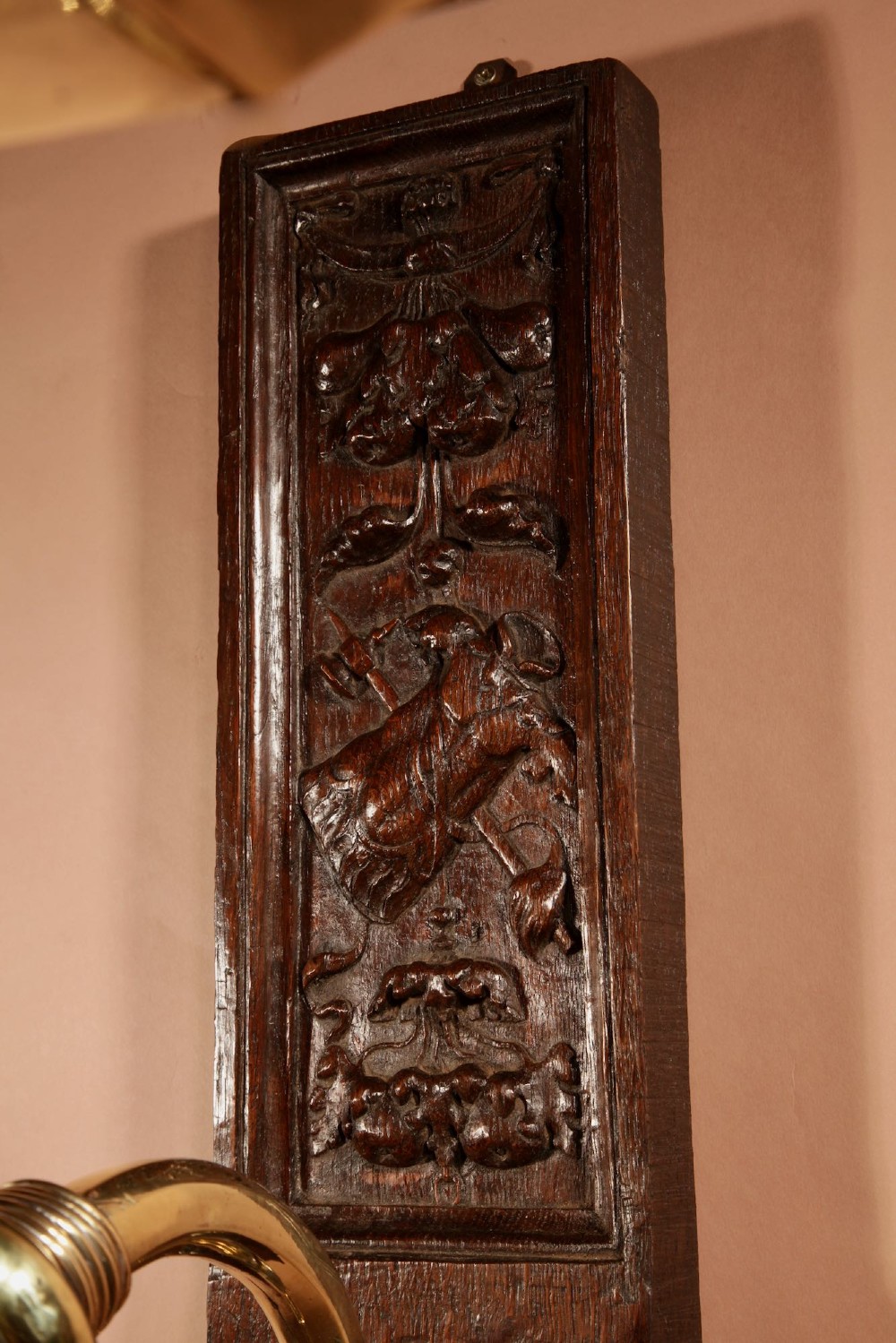 A wall-mounted candle sconce featuring a carved dark oak backboard and a curved brass arm holding a tray with four white candles. View III