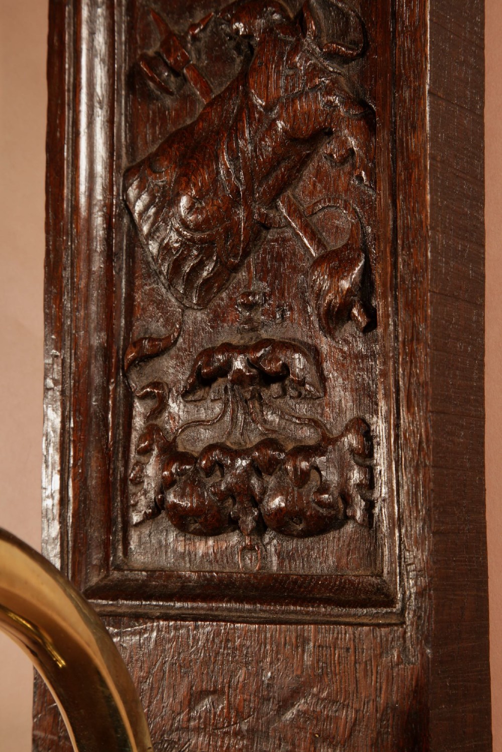 A wall-mounted candle sconce featuring a carved dark oak backboard and a curved brass arm holding a tray with four white candles. View IV