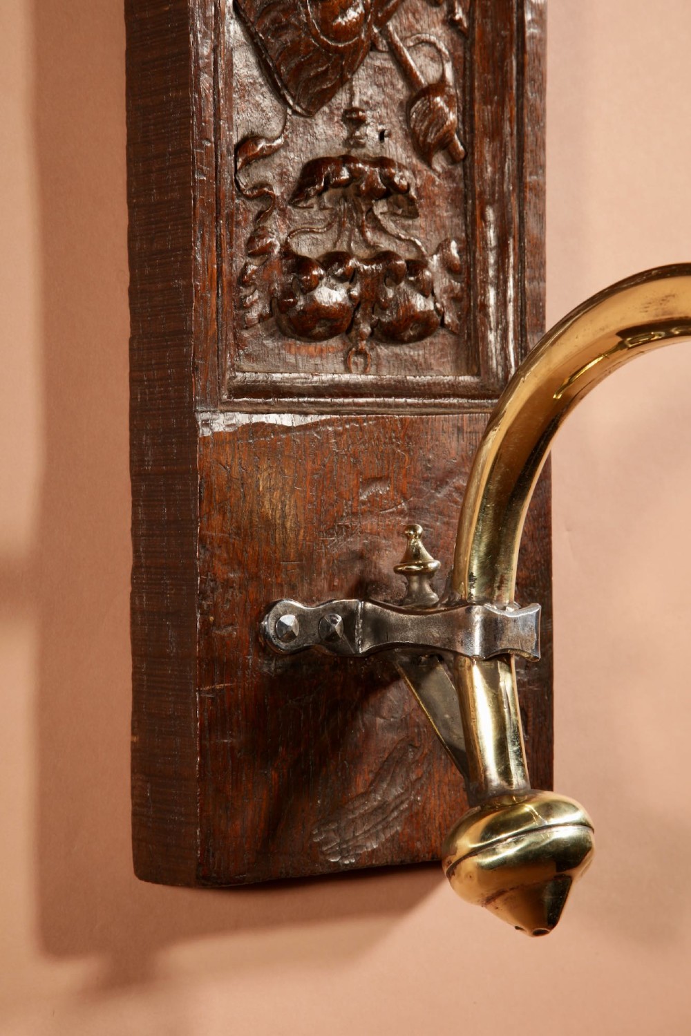 A wall-mounted candle sconce featuring a carved dark oak backboard and a curved brass arm holding a tray with four white candles. View VII