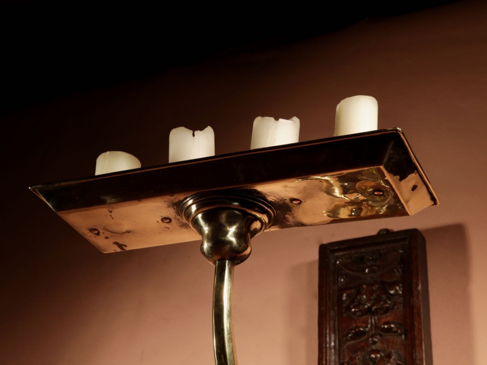A wall-mounted candle sconce featuring a carved dark oak backboard and a curved brass arm holding a tray with four white candles. View IX