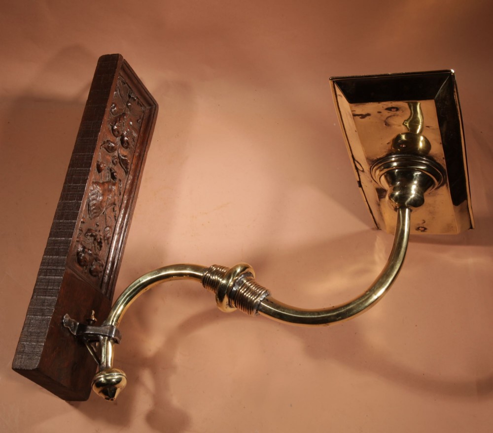 A wall-mounted candle sconce featuring a carved dark oak backboard and a curved brass arm holding a tray with four white candles. View XIII