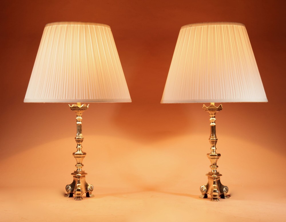 A pair of cast brass table lamps featuring turned baluster shafts, scroll-footed bases, and pleated cream fabric shades. View II