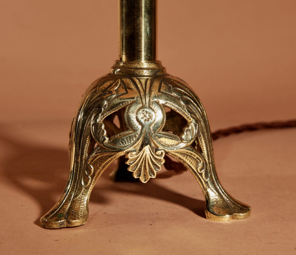 A pair of cast brass table lamps featuring knopped columns, pierced foliage bases, and off-white pleated shades. View IV