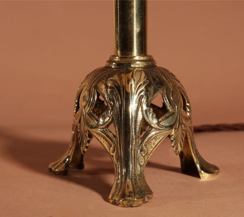A pair of cast brass table lamps featuring knopped columns, pierced foliage bases, and off-white pleated shades. View VI