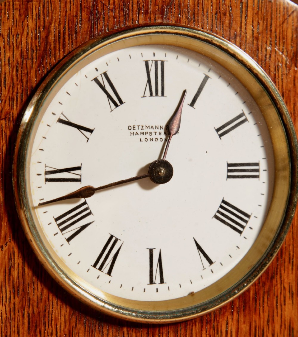 An Arts and Crafts tapered oak mantel clock featuring a white circular dial and wood inlay depicting an owl perched on a pewter crescent moon. View VI
