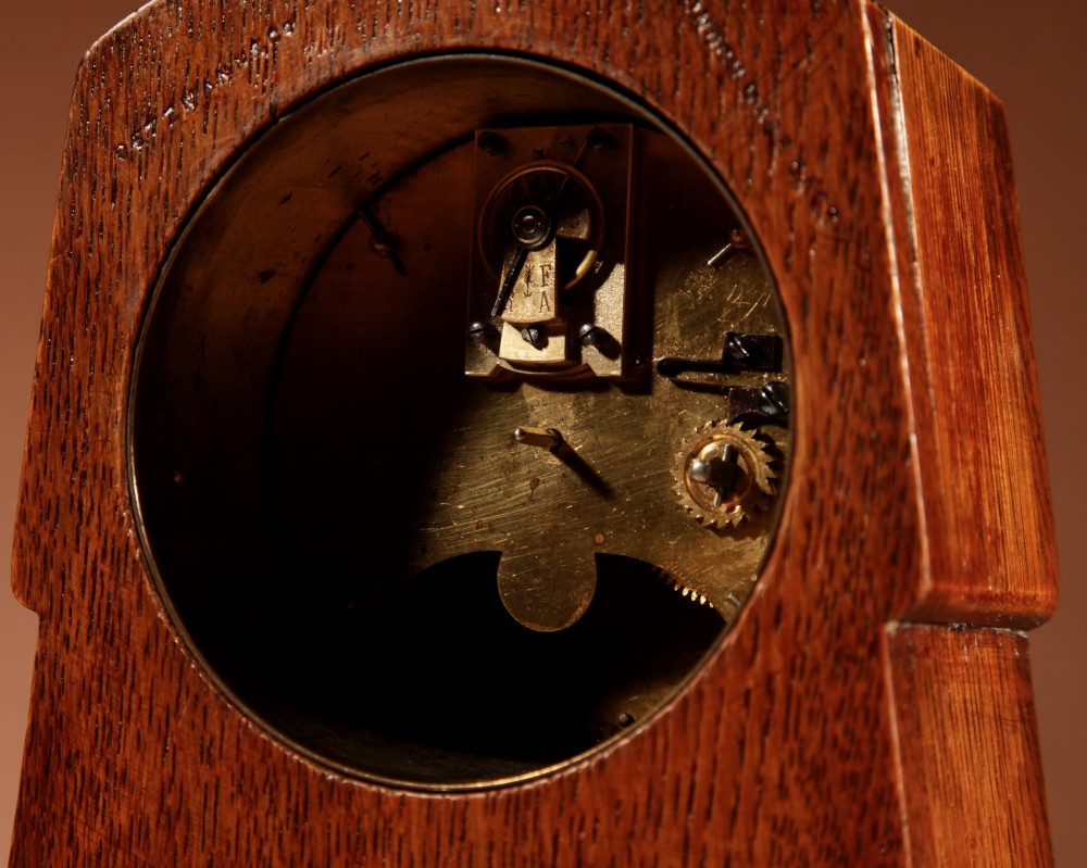 An Arts and Crafts tapered oak mantel clock featuring a white circular dial and wood inlay depicting an owl perched on a pewter crescent moon. View VIII