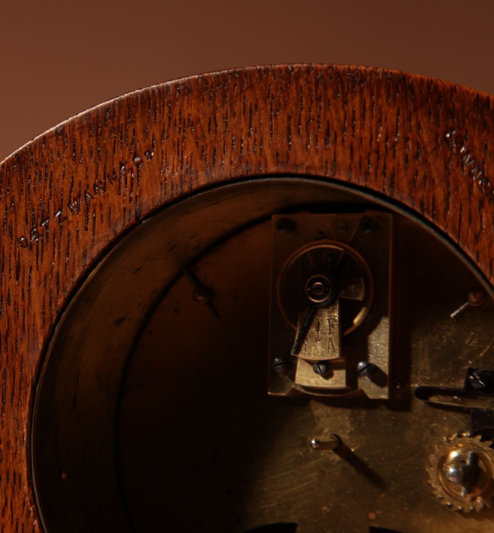 An Arts and Crafts tapered oak mantel clock featuring a white circular dial and wood inlay depicting an owl perched on a pewter crescent moon. View IX