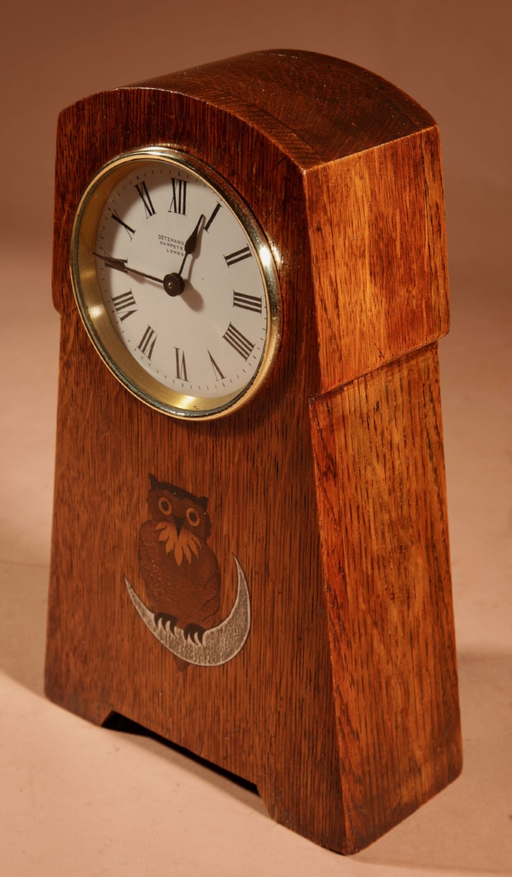 An Arts and Crafts tapered oak mantel clock featuring a white circular dial and wood inlay depicting an owl perched on a pewter crescent moon. View XI