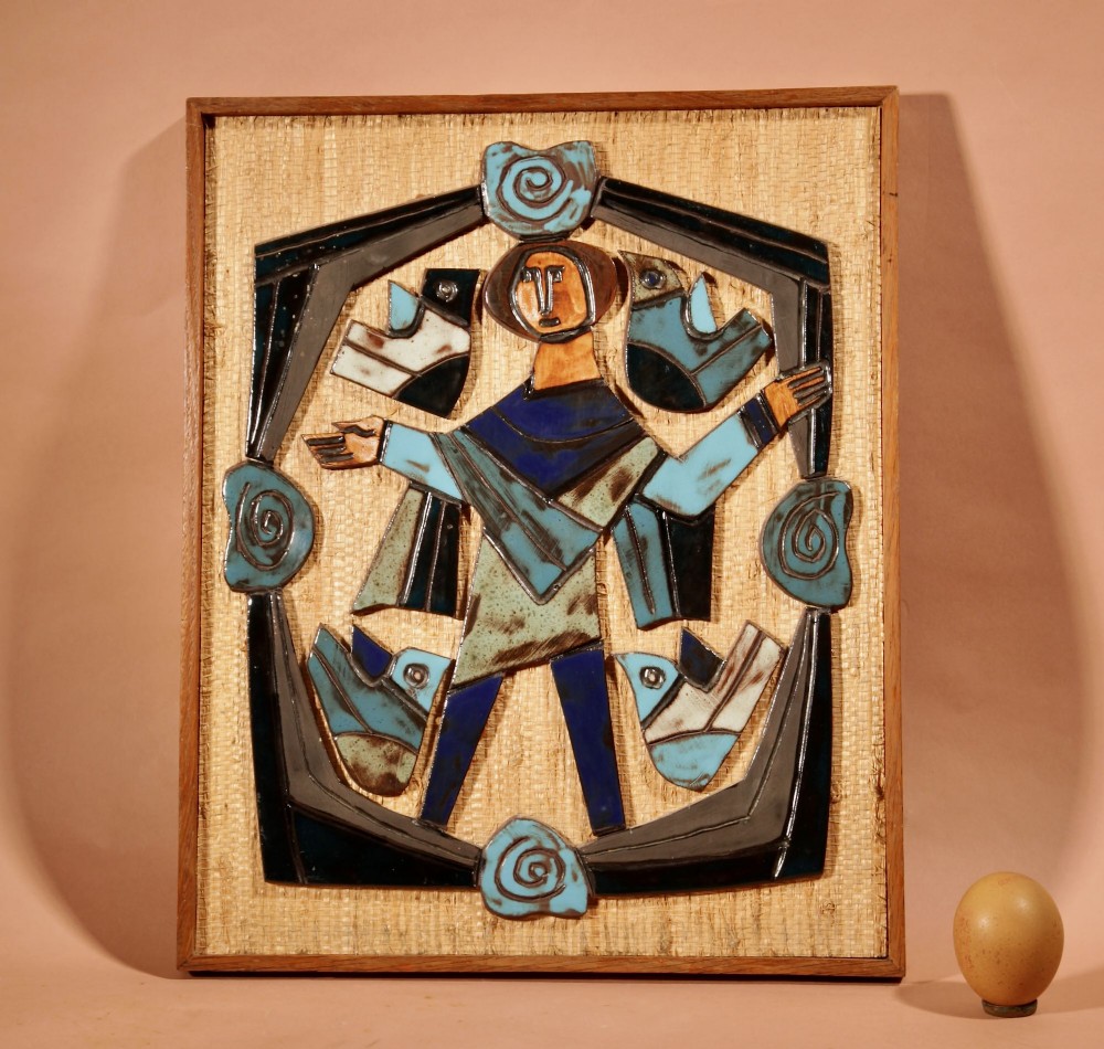 A framed mid-century modern ceramic wall relief featuring stylised figures and birds in turquoise and blue glazes mounted on a woven background. View II
