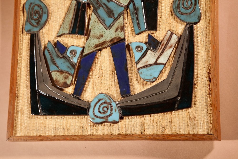 A framed mid-century modern ceramic wall relief featuring stylised figures and birds in turquoise and blue glazes mounted on a woven background. View VI