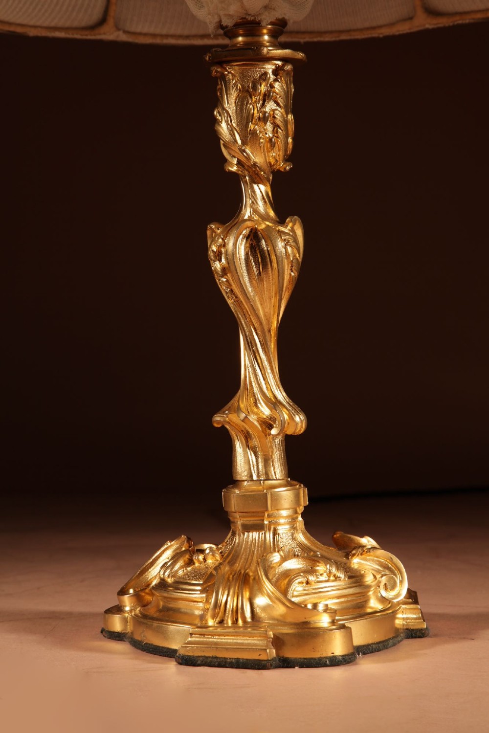 A French Rococo style gilded bronze table lamp featuring an asymmetrical scrolling base and a fitted fabric shade with dark green vertical trim. View IV