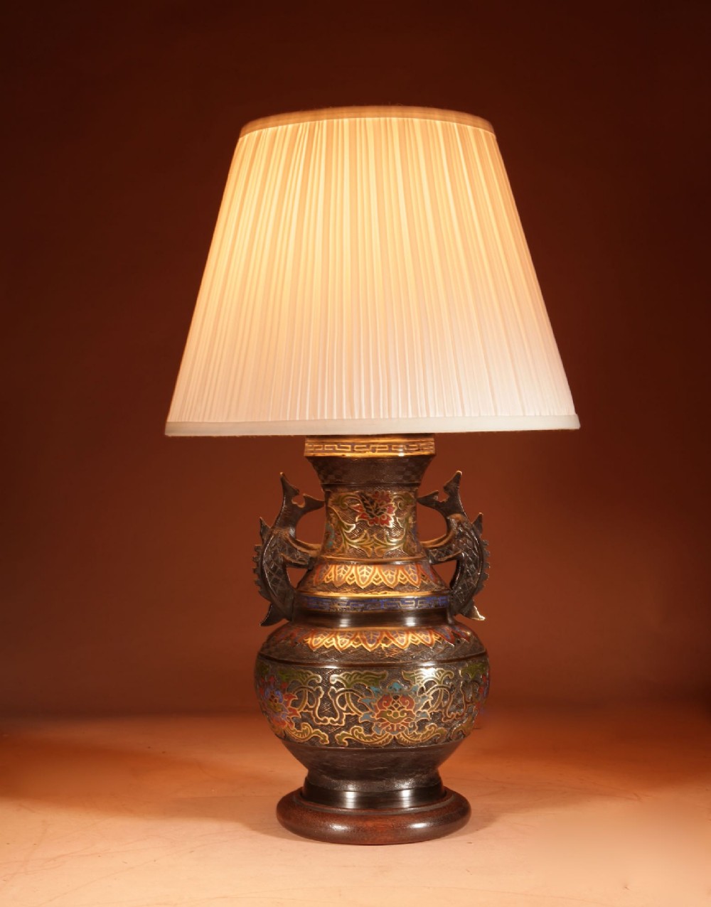 A Japanese champleve bronze vase-form table lamp featuring cast dragon handles, colourful geometric enamel inlay, and a cream pleated shade. View II