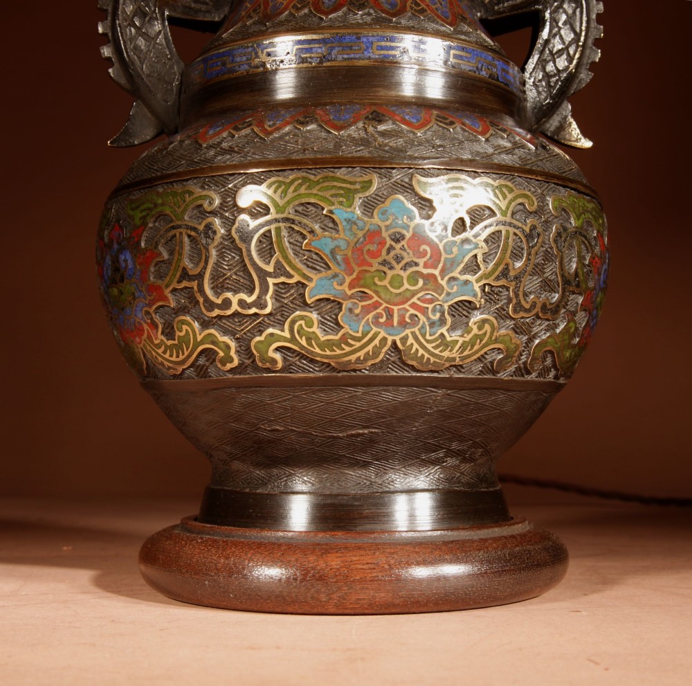 A Japanese champleve bronze vase-form table lamp featuring cast dragon handles, colourful geometric enamel inlay, and a cream pleated shade. View III