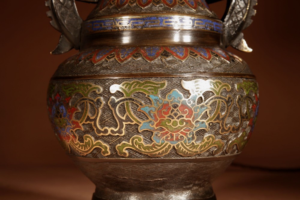 A Japanese champleve bronze vase-form table lamp featuring cast dragon handles, colourful geometric enamel inlay, and a cream pleated shade. View IV