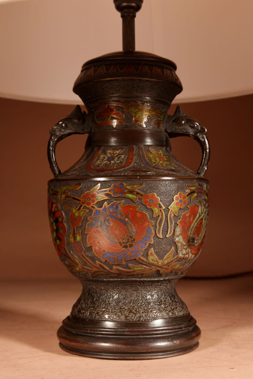 A Japanese champleve bronze urn formatted as a table lamp with polychrome enamel floral patterns, sculpted handles, and a cream pleated shade. View II