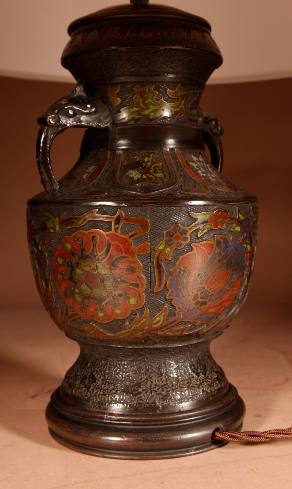 A Japanese champleve bronze urn formatted as a table lamp with polychrome enamel floral patterns, sculpted handles, and a cream pleated shade. View V