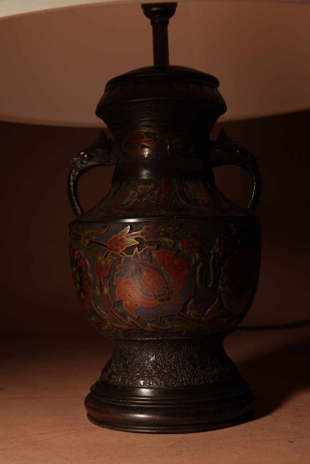 A Japanese champleve bronze urn formatted as a table lamp with polychrome enamel floral patterns, sculpted handles, and a cream pleated shade. View VIII