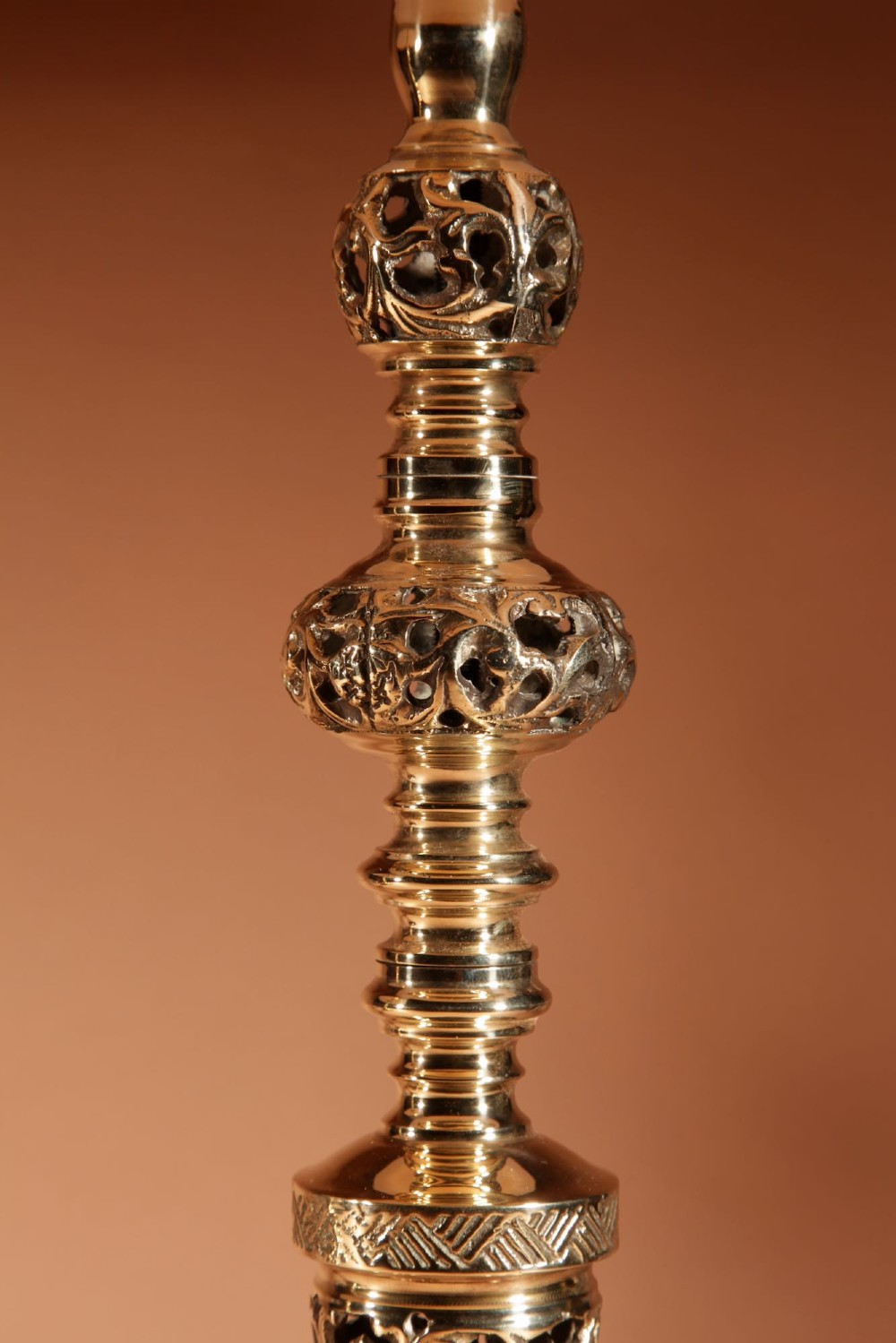 A pair of turned brass table lamps featuring openwork cast detailing and cream pleated shades set against a neutral background. View V