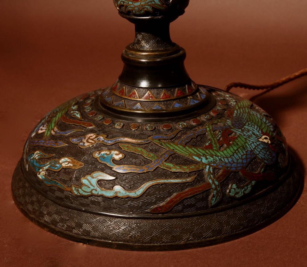 A tall Japanese bronze standard lamp featuring an illuminated red glass lantern shade with enamelled foliage motifs supported on a slender column base. View VII