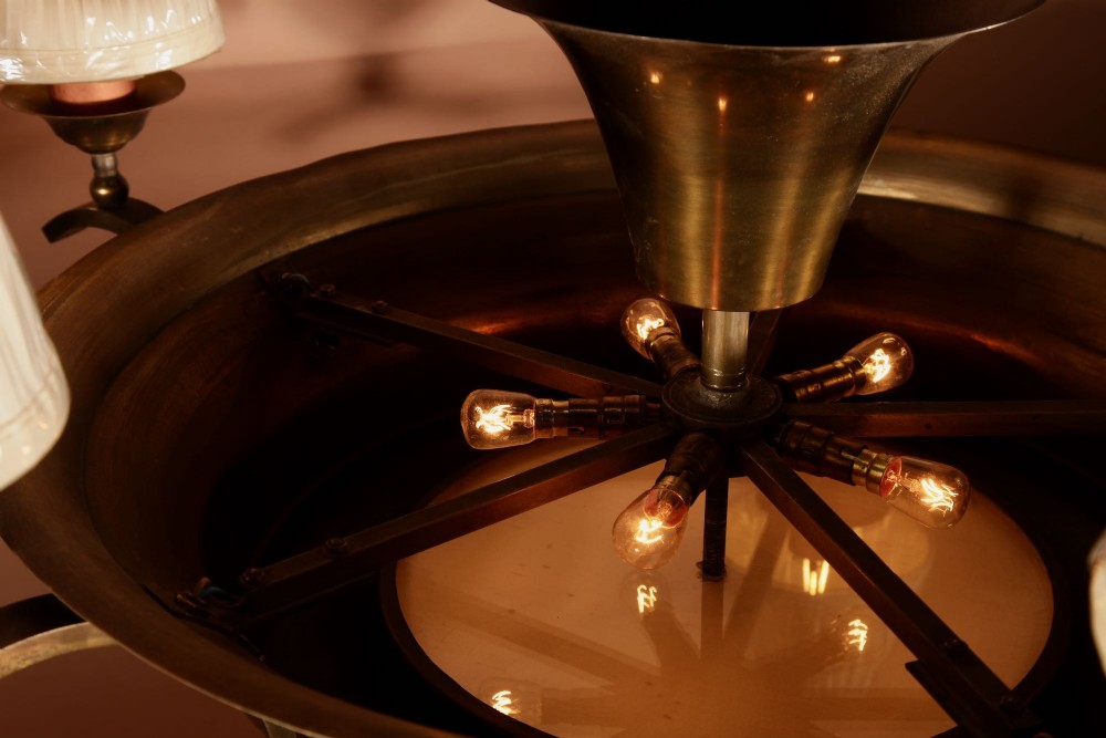An Amsterdam School bronze five-light chandelier featuring a tiered central column and small pleated lampshades. View X