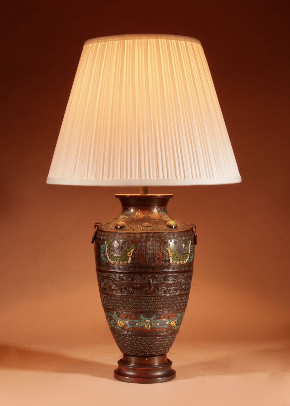A Japanese cast bronze table lamp decorated with polychrome champleve enamel band motifs and fitted with a pleated cream shade. View II