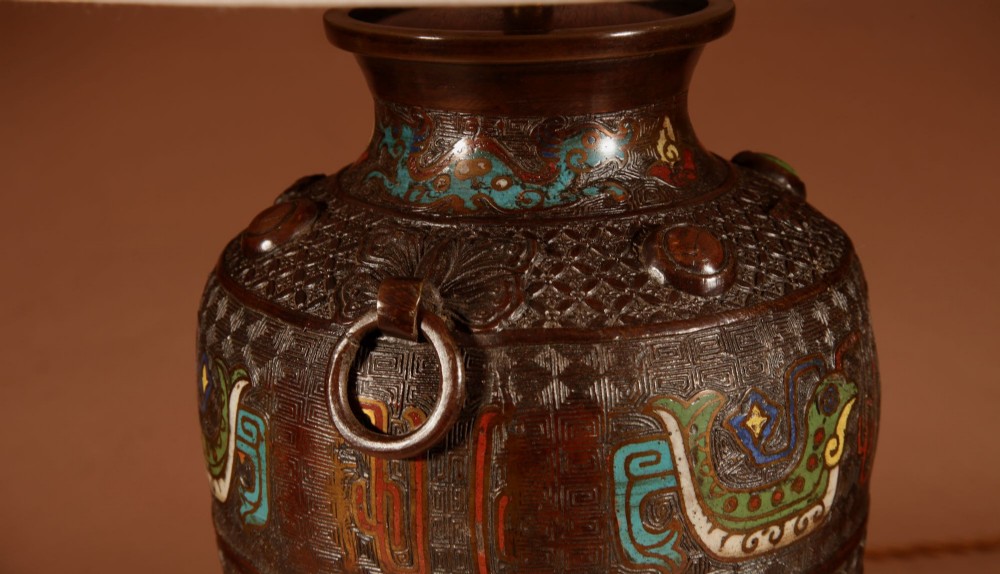 A Japanese cast bronze table lamp decorated with polychrome champleve enamel band motifs and fitted with a pleated cream shade. View VI