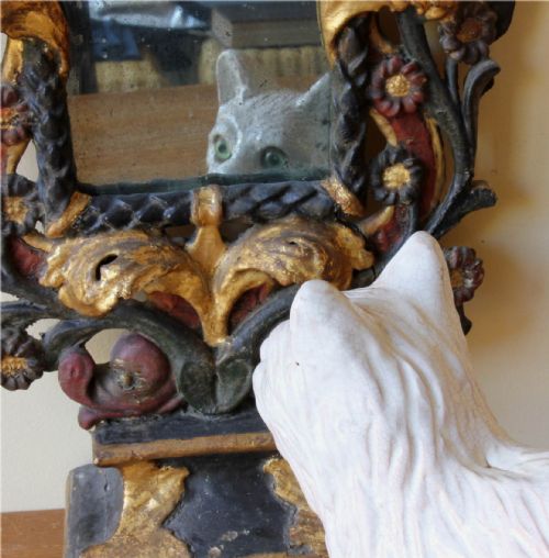 fig 4. A cream-glazed terracotta cat figure depicted in a crouching pose featuring bright green glass eyes.