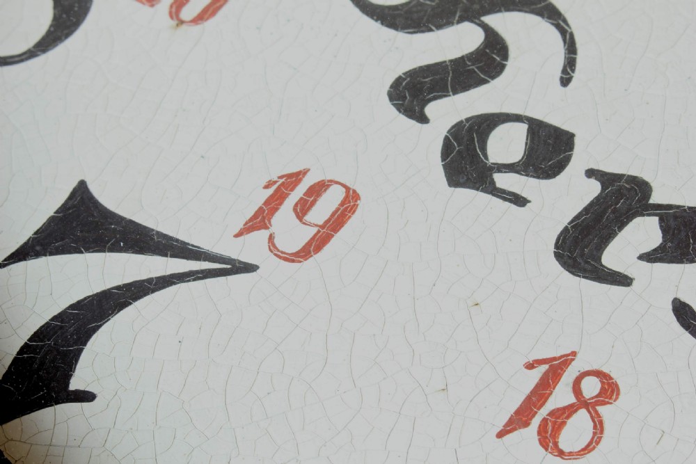 A large double-sided metal trade sign shaped like an oversized pocket watch, featuring black numerals, red clock hands, and an attached side mounting bracket. View VIII