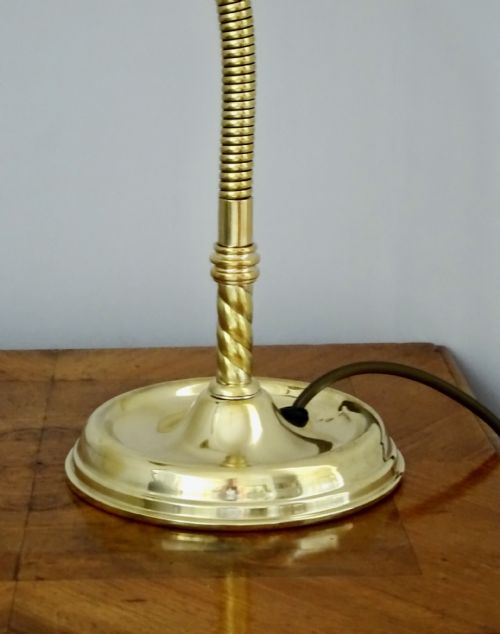 fig 1. An Art Deco polished brass gooseneck desk lamp featuring an adjustable flexible arm, domed shade, and round stepped base.