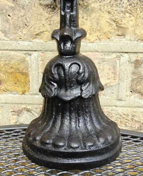 fig 1. A Victorian black cast iron doorstop with a flared weighted base, central leaf column, and a ribbon bow motif top handle.